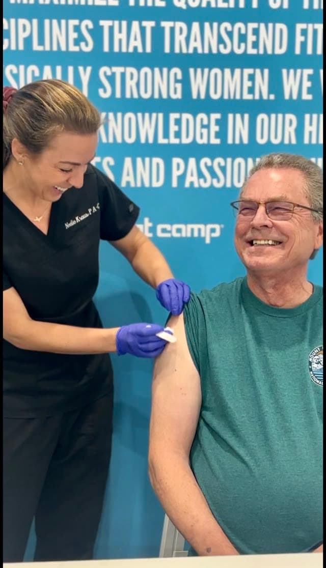 Noelle giving a wellness injection to a smiling long-time patient